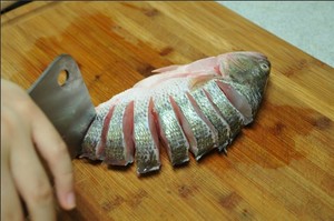 將鱸魚清洗干凈，從脊椎處切斷至腹部，腹部保留1cm左右不要切斷。