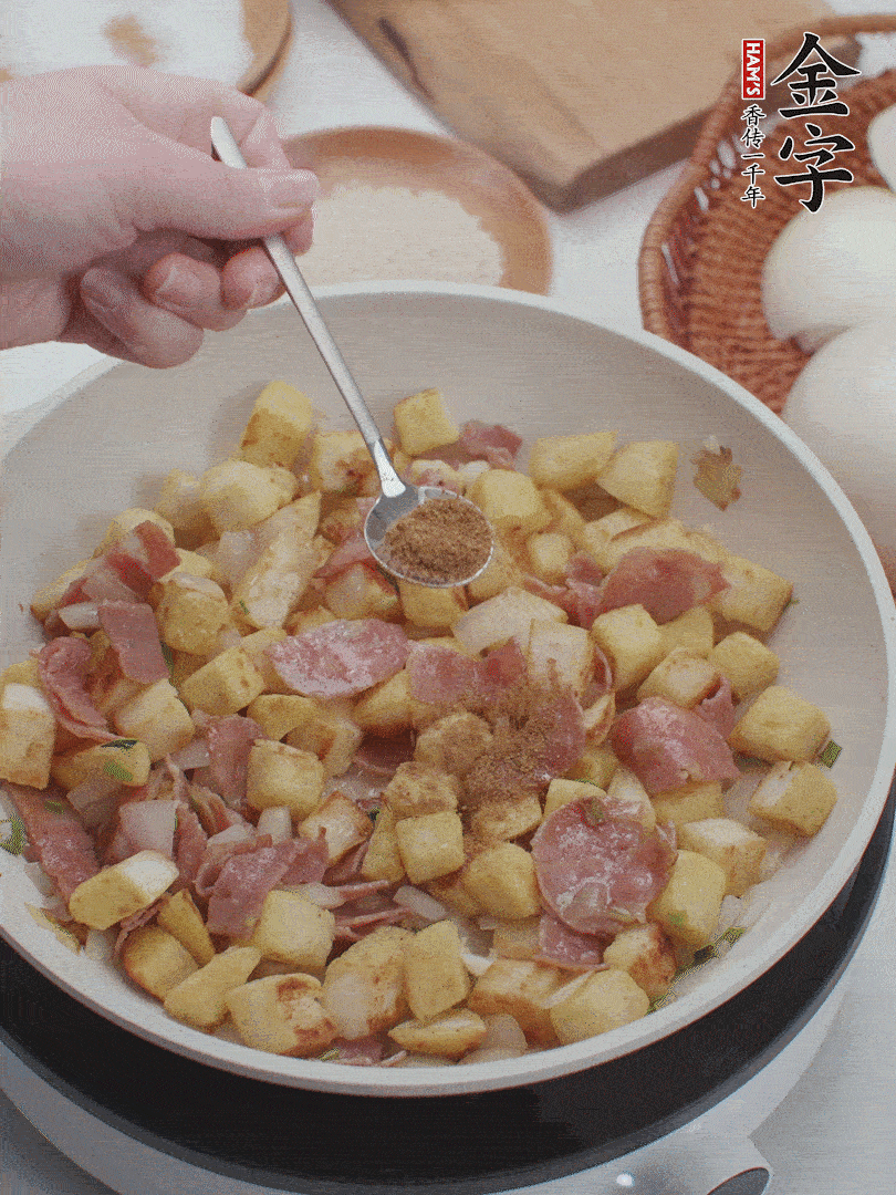 起鍋少油，煸香洋蔥丁、蔥白，加入金字培根火腿翻炒幾下，再加入饅頭丁、1小勺孜然粉、少許鹽翻炒均勻并鋪平。